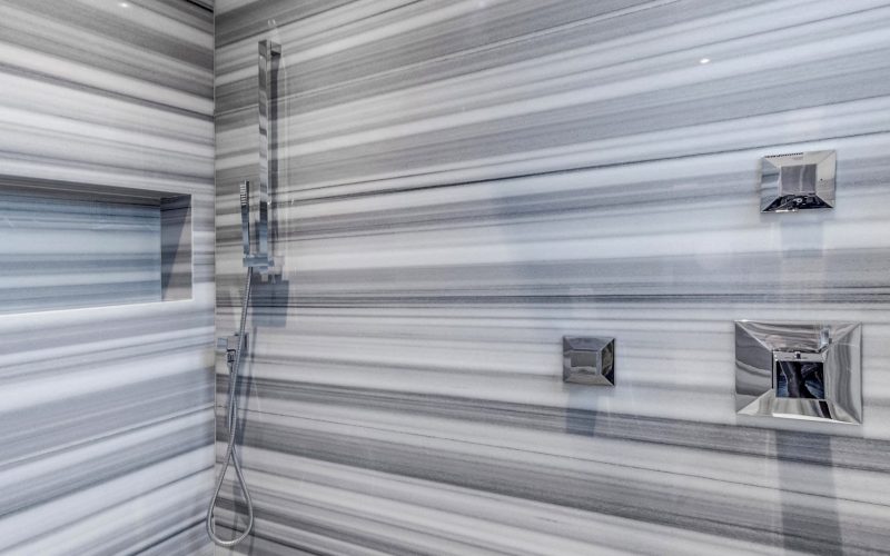Bathroom with grey and white strip stone floor, matching wall cladding, and shower